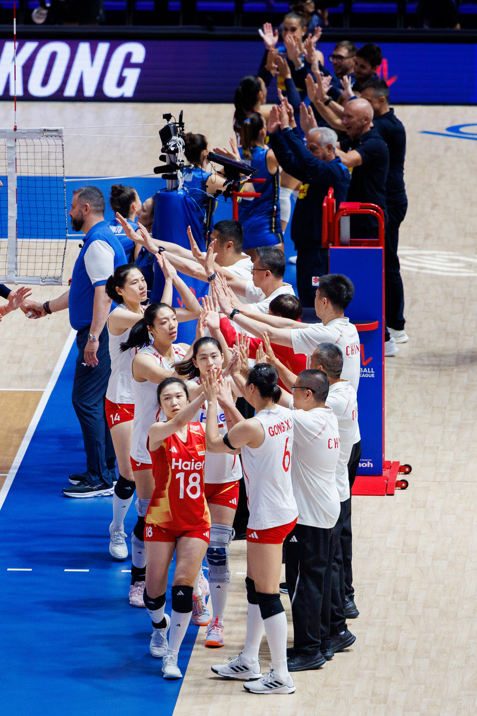 Volleyball players high-five coaching staff along the VNL sideline
